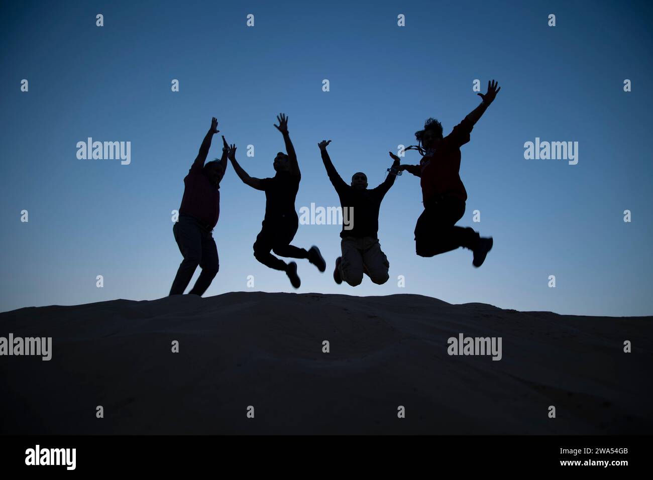 29 dicembre 2023, Dubai, Emirati Arabi Uniti. Gruppo di persone che saltano in alto sulle dune. Foto Stock
