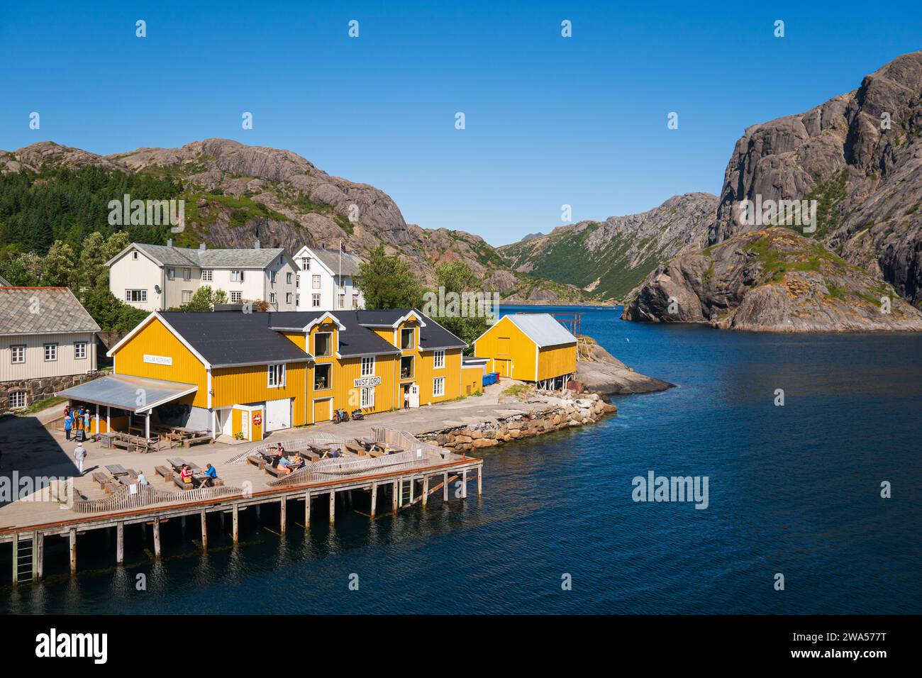 Il piccolo villaggio di Nusfjord sulla costa meridionale del Lofoten, in una luminosa giornata estiva, barche da pesca e barche a vela insieme a case colorate. Foto Stock