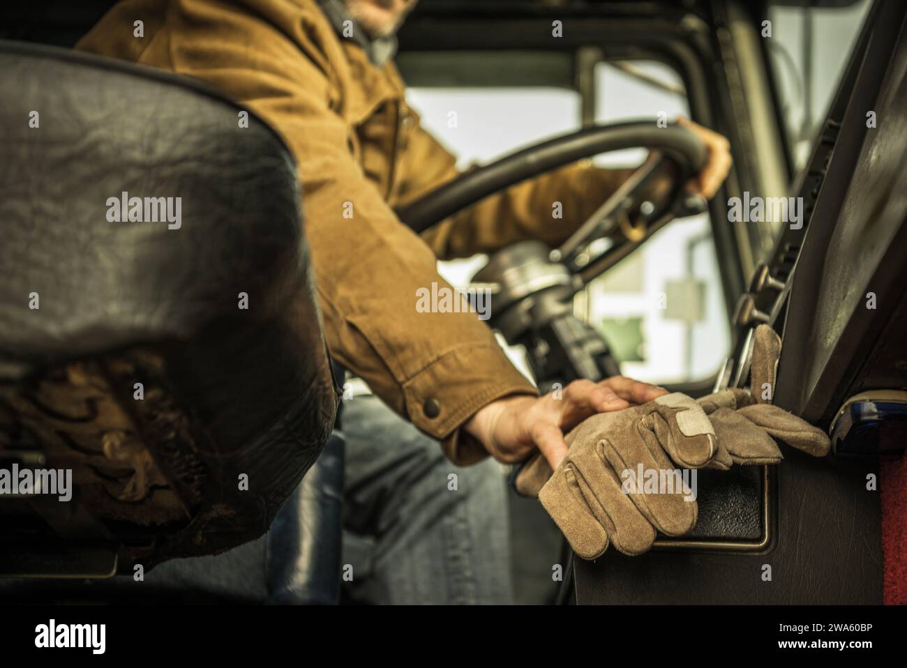 Conducente di semi-camion dietro il suo classico volante del veicolo. Guanti di sicurezza in First Plan. Foto Stock