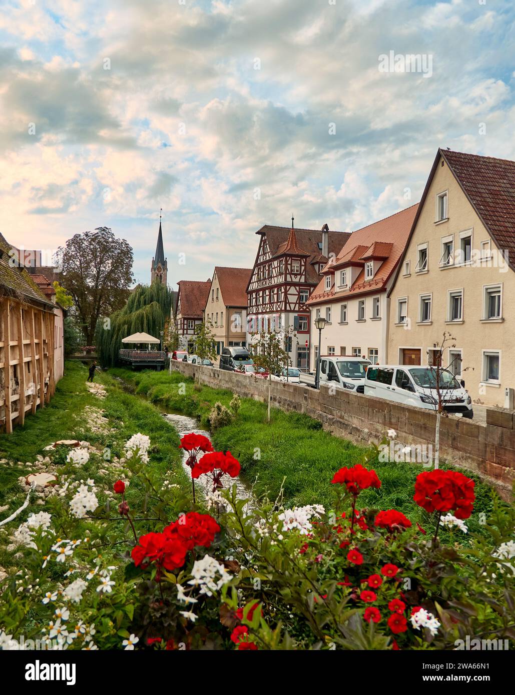 Composizioni floreali nella Bachgasse nel centro storico di Schwabach, di fronte a una romantica fila di case e a un piccolo ruscello Foto Stock