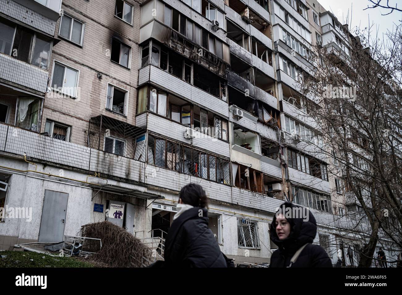 Kiev, Ucraina. 2 gennaio 2024. Nel quartiere residenziale di Solomyanka, un edificio di 9 piani con 10 gradini è stato colpito questa mattina presto. Due persone anziane sono state uccise e altri 49 residenti feriti.? I residenti passano davanti al loro edificio distrutto. Durante la notte, la Russia lanciò un grande attacco aereo contro l'Ucraina. Durante la notte la Russia lanciò un vasto attacco aereo contro l'Ucraina. Un'onda iniziale di 35 droni Shahed è stata lanciata alle 2. Crediti: LE PICTORIUM/Alamy Live News Foto Stock