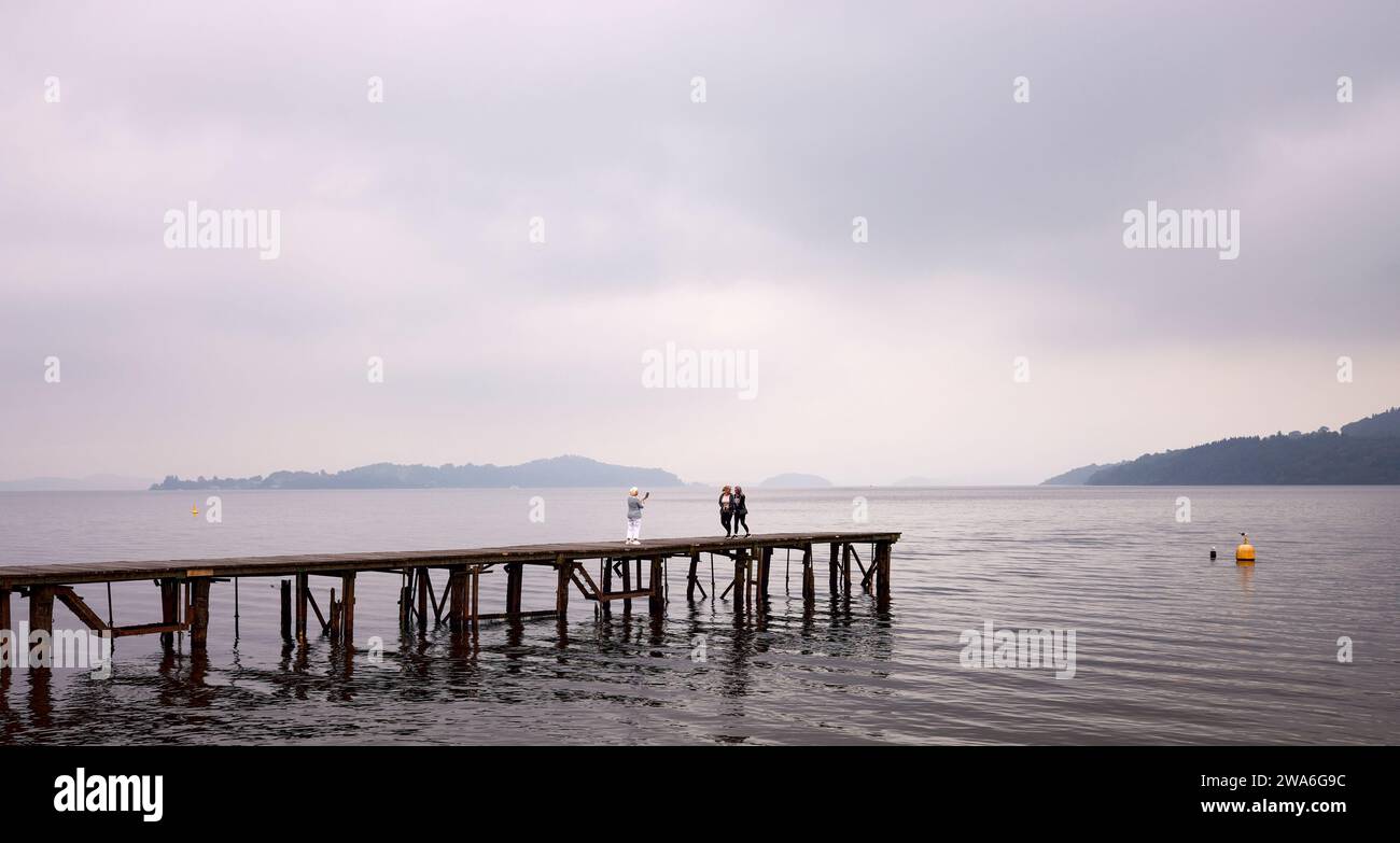 3 adulti donne si godono del tempo insieme sul molo di legno al Duck Bay Hotel sul Loch Lomond, Scozia Foto Stock