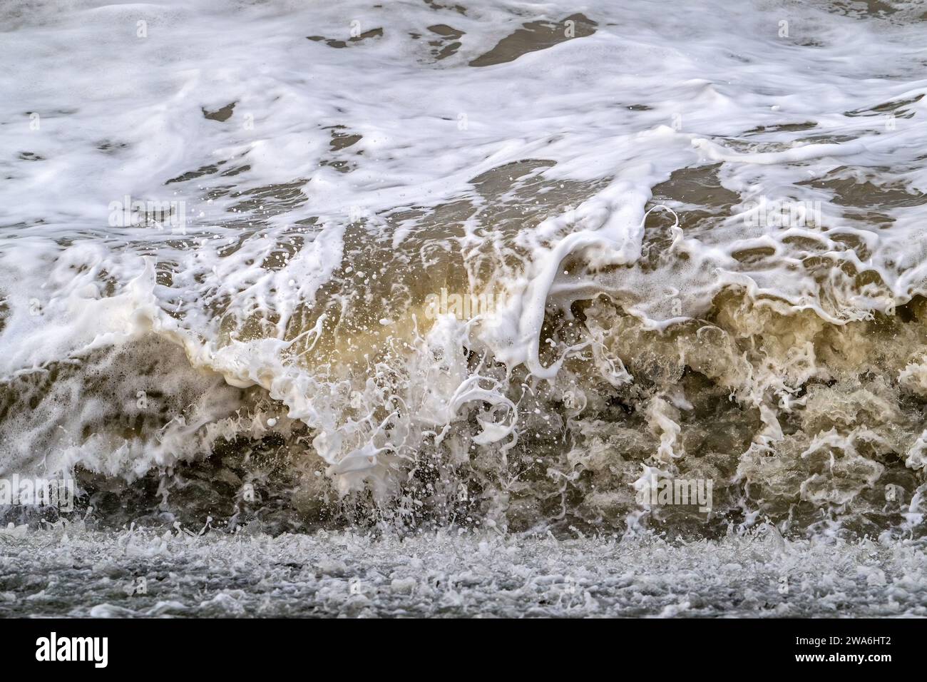 Onde che si infrangono/rotolano sulla spiaggia durante la tempesta invernale lungo la costa del Mare del Nord in Zelanda, Paesi Bassi Foto Stock