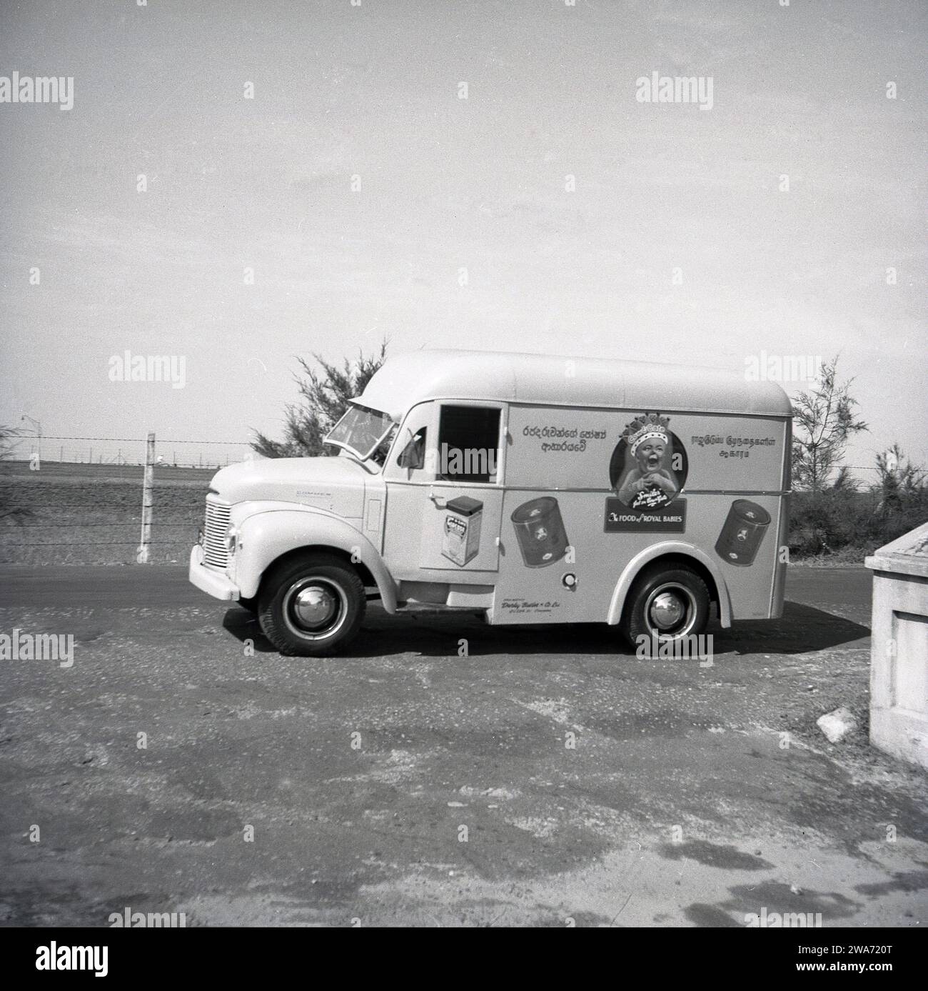 1953, storico, un furgone Commer su una strada a Colombo, Celyon, Asia meridionale. Sul lato del furgone, un bambino sorridente che indossa una corona con lo strapline, "The Food of Royal Babies" e barattoli di mucca e latte alimentare. Agenti unici: Darley Butler & Co Ltd, Queen St, Colombo. The Cow & Gate 'smiler', un bambino felice e dall'aspetto sano, è apparso per la prima volta sulle confezioni e sugli annunci pubblicitari dei prodotti negli anni '1930 Il "bambino reale; con una corona sulla testa risale al 1937 e l'incoronazione di Briitsh re Giorgio vi, quando la compagnia di diari inglese iniziò a usare la "Royal Association" per sostenere la loro formula di latte per bambini. Foto Stock