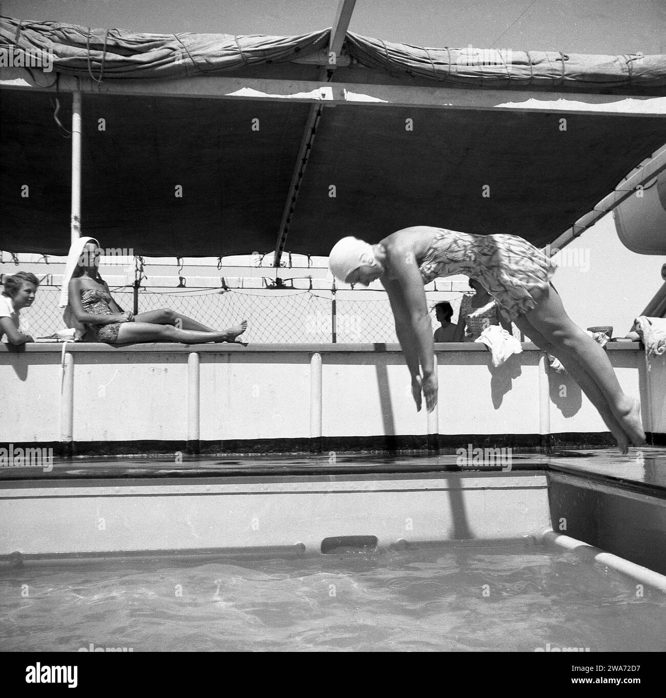 1953, storica, una giovane donna in vacanza a Ceylon (Sri Lanka), in costume da bagno dell'epoca e cappello da bagno, tuffandosi in una piscina all'aperto all'aperto su una barca. Situata nell'Oceano Indiano nell'Asia meridionale, l'isola divenne una Repubblica Democratica Socialista nel 1972 e cambiò il suo nome in Sri Lanka. Foto Stock