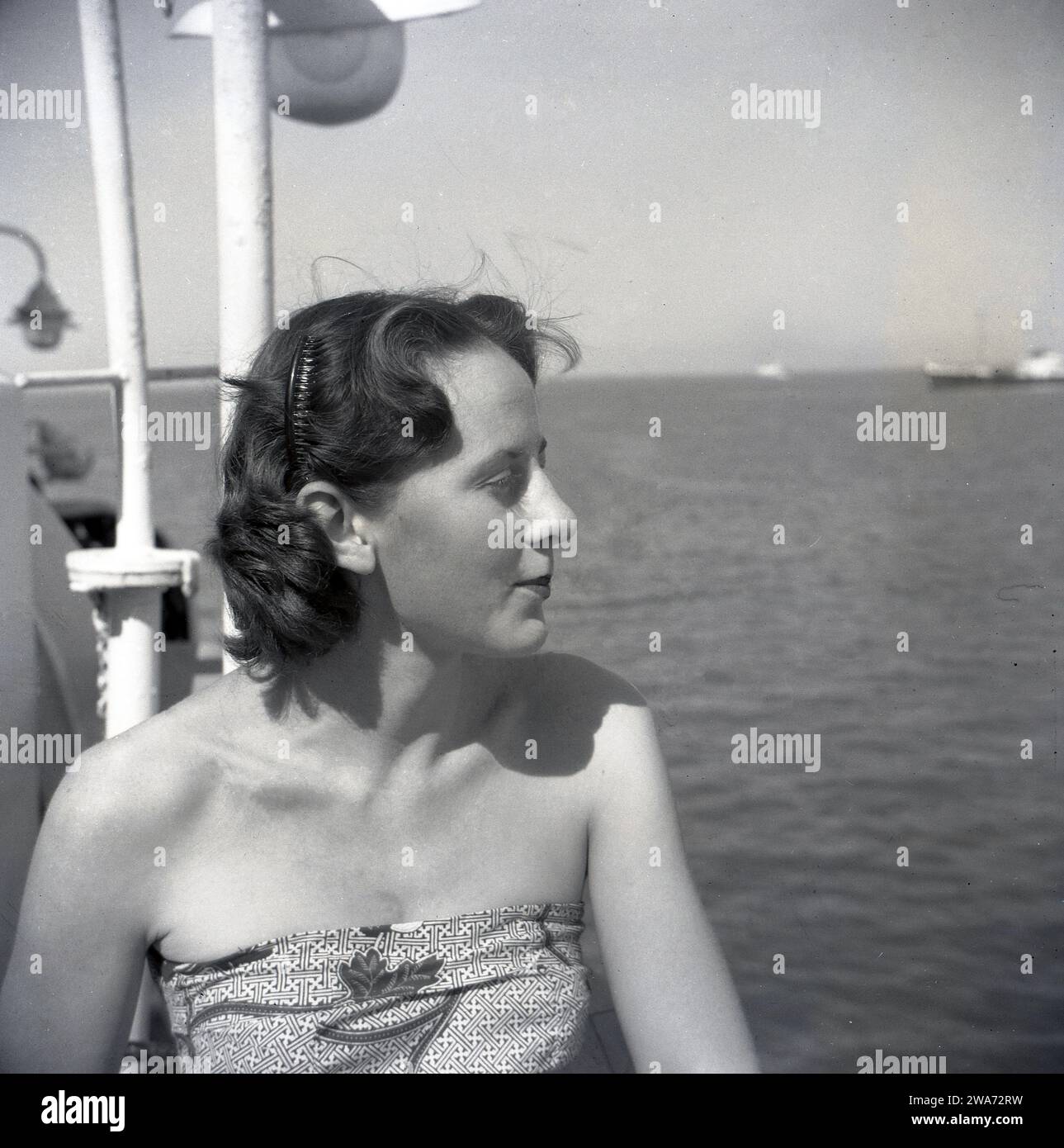 1953, storica giovane donna in vacanza sull'isola di Ceylon (Sri Lanka), seduta su una barca che guarda al mare. Situata nell'Oceano Indiano nell'Asia meridionale, l'isola divenne una Repubblica Democratica Socialista nel 1972 e cambiò il suo nome in Sri Lanka. Foto Stock