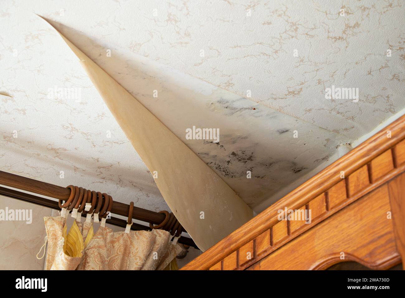 La carta da parati si staccò sul soffitto nella cucina nell'angolo dopo l'alluvione, ristrutturando l'appartamento Foto Stock