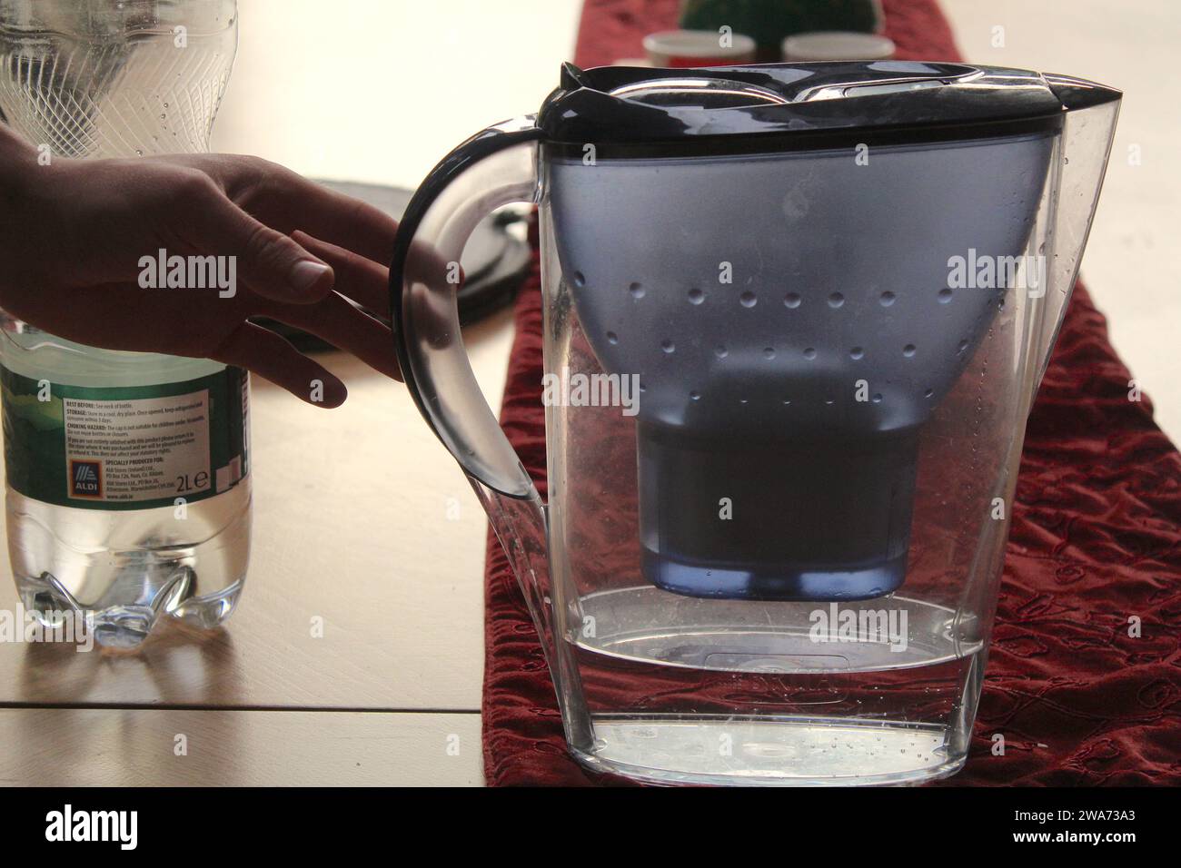 Dublino, Irlanda - 3 gennaio 2024: Una foto ravvicinata di una persona che sale su un tavolo di legno per afferrare una caraffa d'acqua. Foto Stock