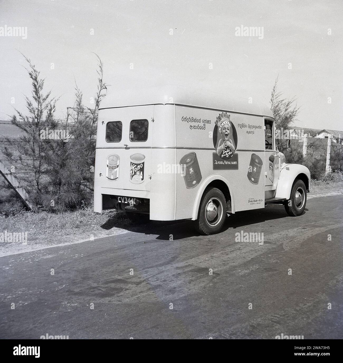 1953, storico, un furgone Commer su una strada a Colombo, Celyon, Asia meridionale. Sul lato del furgone, un bambino sorridente che indossa una corona con lo strapline, "The Food of Royal Babies" e barattoli di mucca e latte alimentare. Agenti unici: Darley Butler & Co Ltd, Queen St, Colombo. The Cow & Gate 'smiler', un bambino felice e dall'aspetto sano, è apparso per la prima volta sulle confezioni e sugli annunci pubblicitari dei prodotti negli anni '1930 Il "bambino reale; con una corona sulla testa risale al 1937 e l'incoronazione di Briitsh re Giorgio vi, quando la compagnia di diari inglese iniziò a usare la "Royal Association" per sostenere la loro formula di latte per bambini. Foto Stock