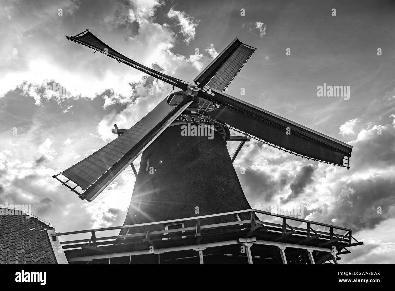 il sole splende su un vecchio mulino a vento olandese in bianco e nero Foto Stock