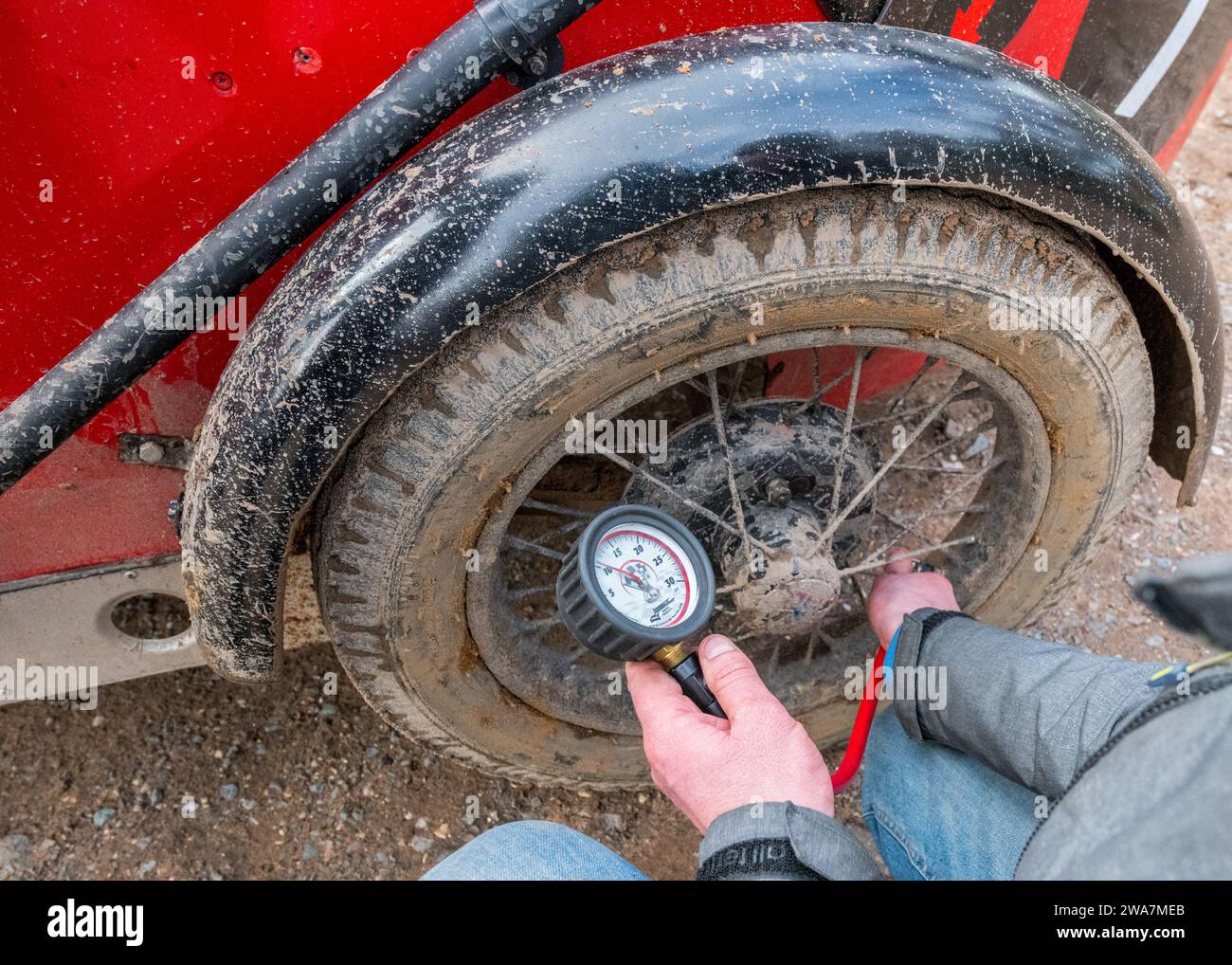 Guida o concorrente che controlla la pressione degli pneumatici su una Austin 7 pre-bellica prima dell'inizio della prova in salita di Dave Wilcox. Foto Stock