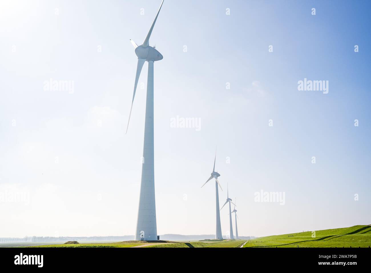 turbina eolica in campo in una giornata di sole con l'oceano sullo sfondo Foto Stock