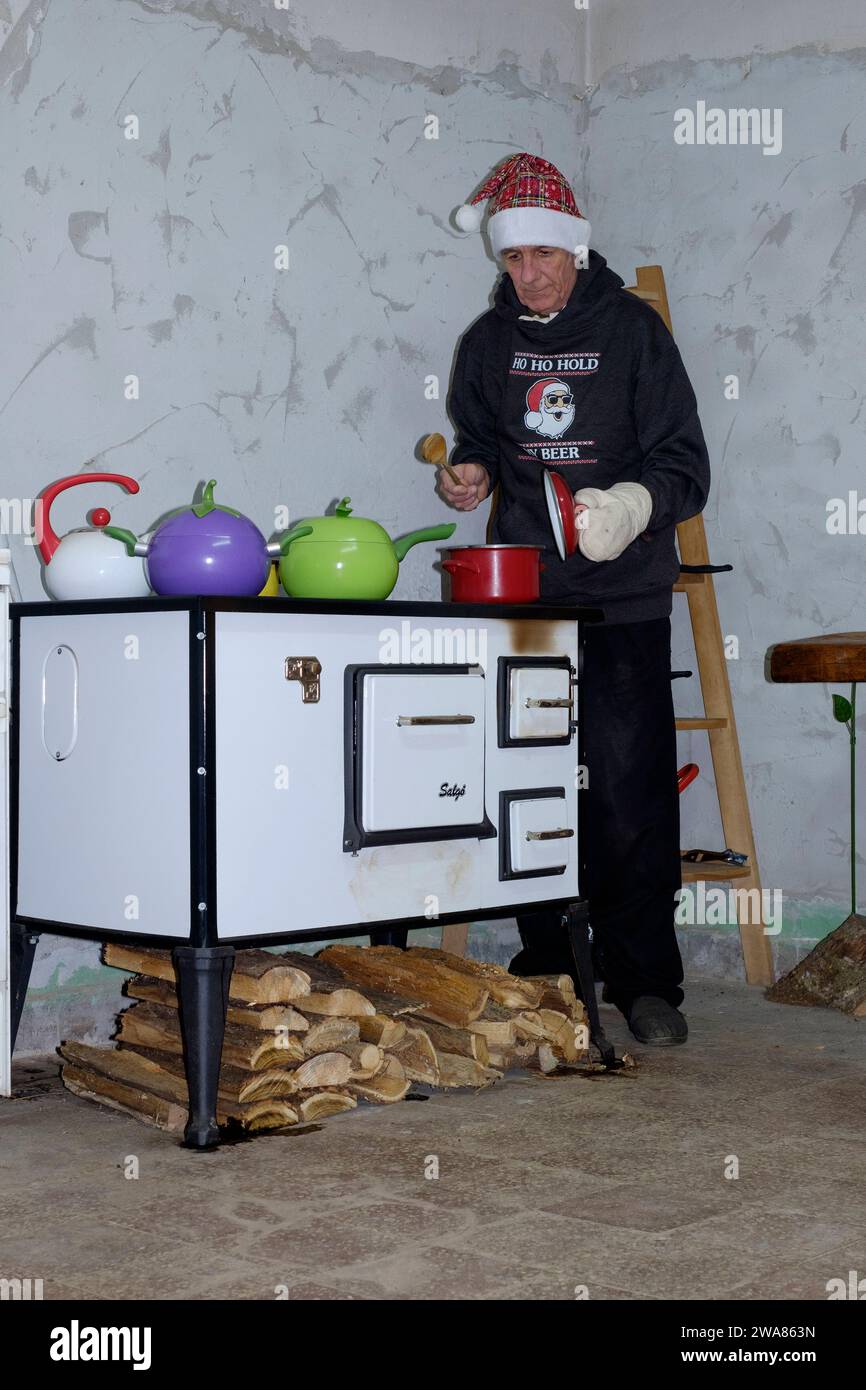 uomo maturo usando una stufa a legna tradizionale per cucinare una cena arrosto in casa rurale cucina zala contea ungheria Foto Stock