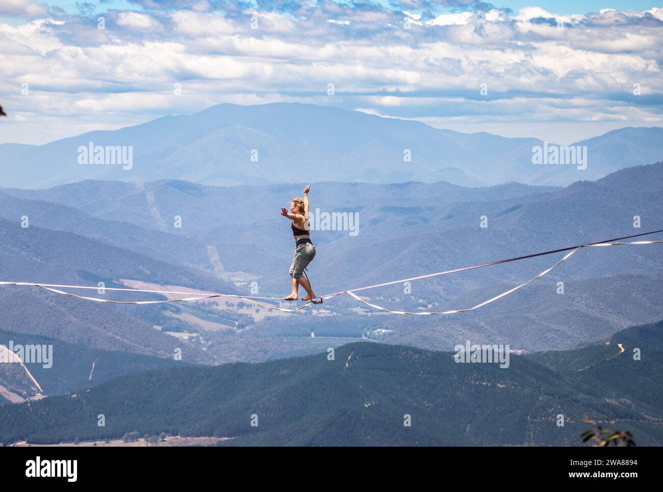 Slacklining attraverso le Alpi Australiane. Una slackliner in equilibrio in alto a Mount Buffalo, Victoria, Australia. Foto Stock