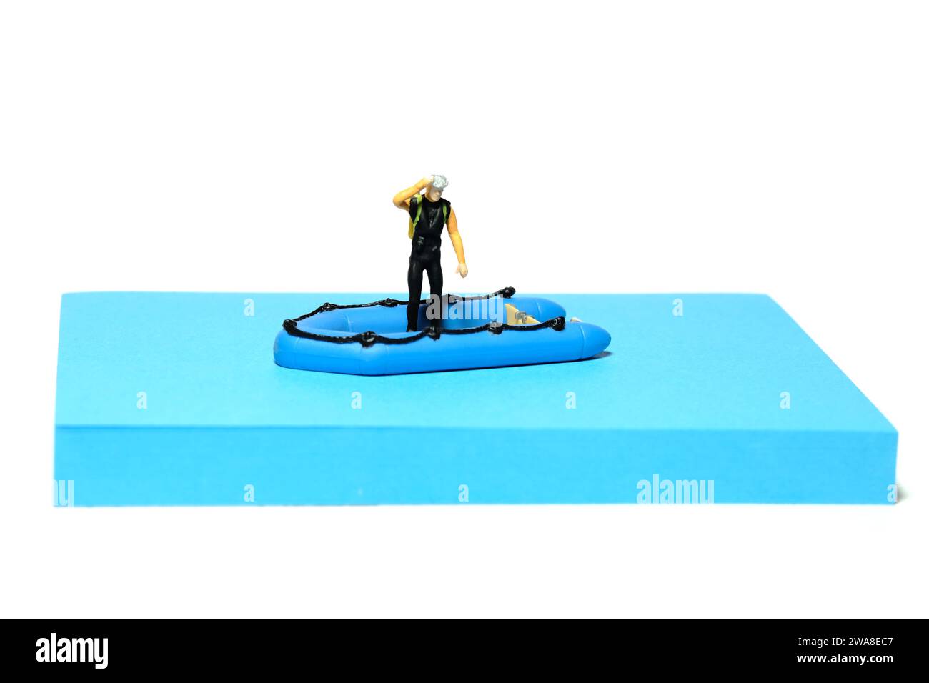 Fotografia creativa di figure giocattolo per persone in miniatura. Installazione delle note adesive. Preparazione per immersioni subacquee sopra gommoni. Isolato sul retro bianco Foto Stock