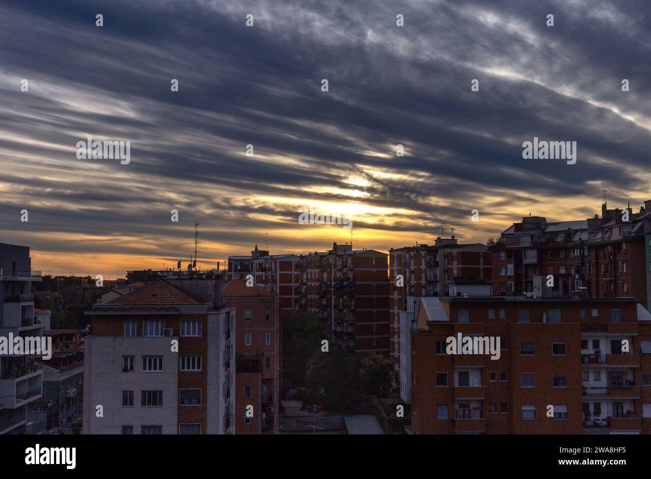 Lo skyline della città diventa una splendida silhouette mentre le sfumature drammatiche di un tramonto ardente dipingono il cielo sopra gli edifici. Foto Stock