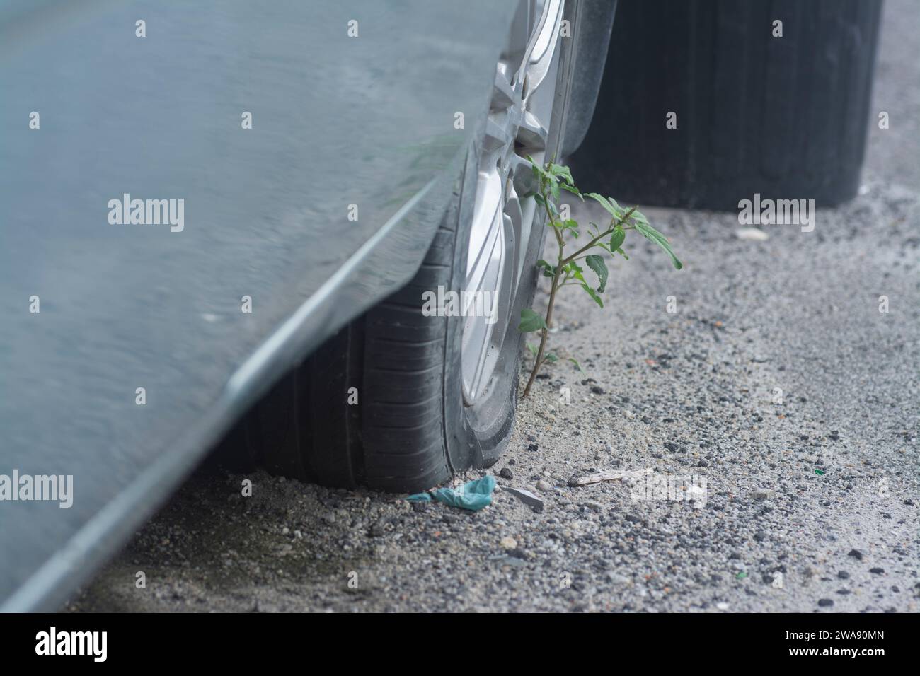 Ruota con pneumatico quasi piatto sul lato della strada. Foto Stock