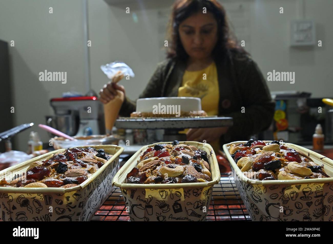 Sutapa Choudhary, un'artista e insegnante di torte, che prepara torte nel suo salone di torte, "CREMOSE DELIZIE". C'è una grande domanda di torte durante il periodo natalizio ad Agartala. Tripura, India. Foto Stock