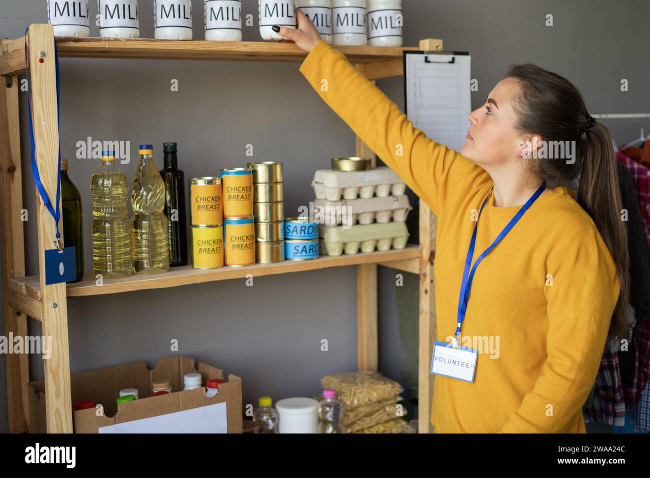Volontaria donna felice con cibo sullo scaffale presso il centro di distribuzione o assistenza o donazione dei rifugiati. Beneficenza, donazione e volontariato Foto Stock