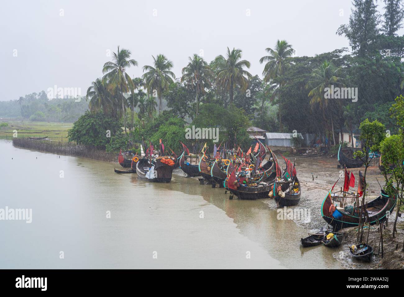 Vista del paesaggio delle tradizionali barche di legno conosciute come barche lunari sulla riva del fiume sotto la pioggia, Cox's Bazar, Bangladesh Foto Stock