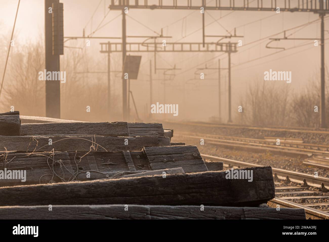 Un mucchio di vecchi dormitori di fronte a una stazione ferroviaria o a un binario di fianco. I vecchi dormienti fanno il posto ai nuovi. Mattina presto, nebbiosa mattina Foto Stock