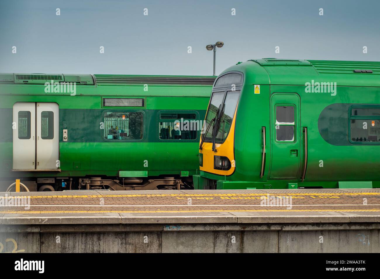 Vista laterale dei treni sulla stazione ferroviaria di Drogheda macbride in irlanda, su una linea da Dublino a Belfast. Banchine ferroviarie e treni che passano su una soleggiata strada Foto Stock