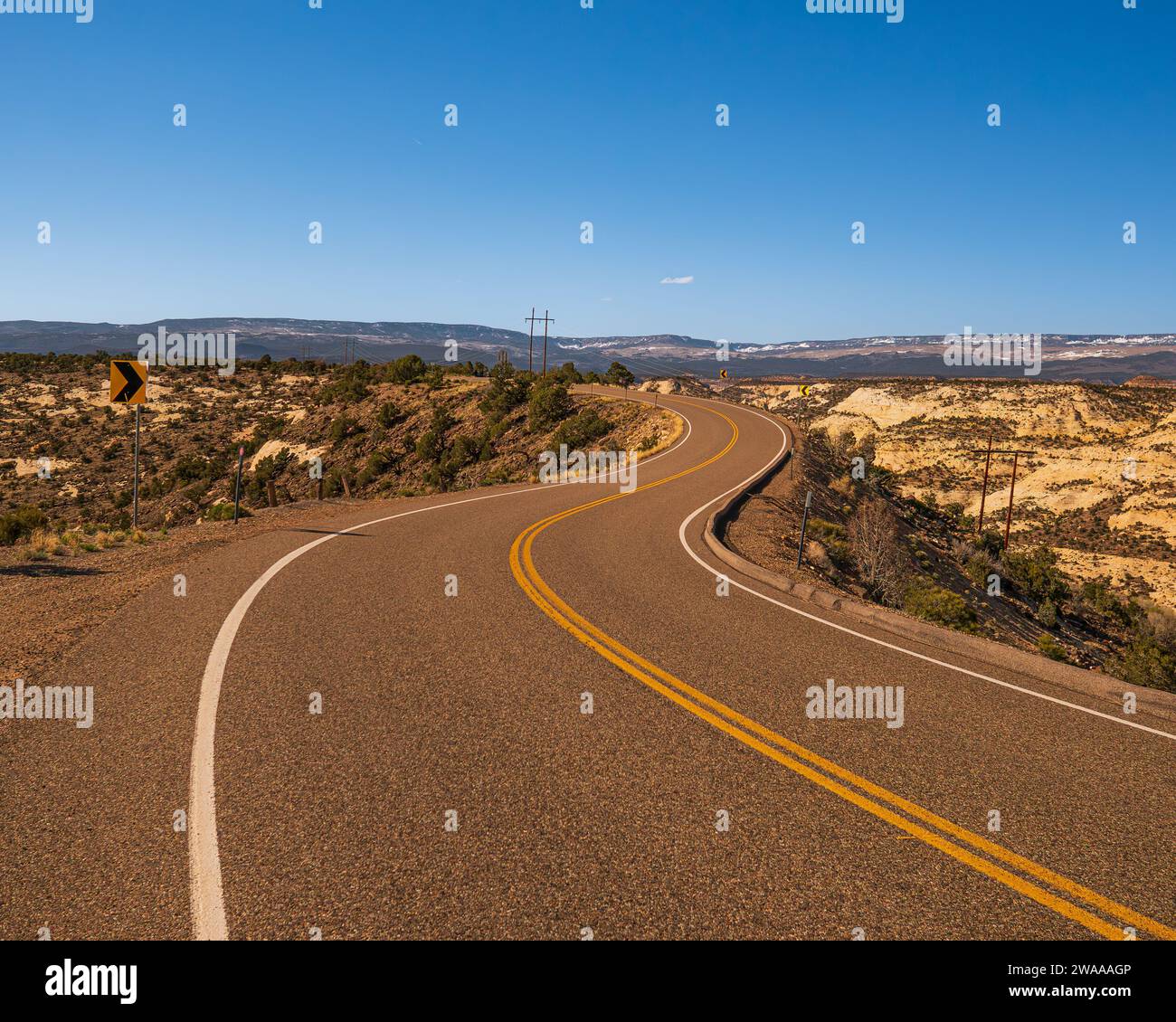 Strada tortuosa in un paesaggio desertico nello Utah, Stati Uniti, vicino a Escalante e al monumento nazionale Grand Staircase. Cielo azzurro e strada vuota. Foto Stock