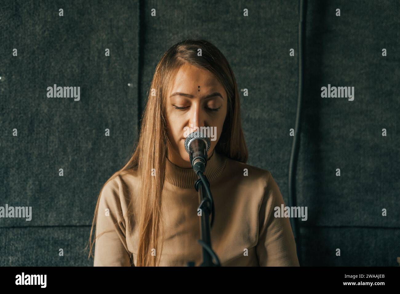 Donna che registra podcast online con microscopio per i social media o trasmette in streaming le stazioni radio. Foto Stock