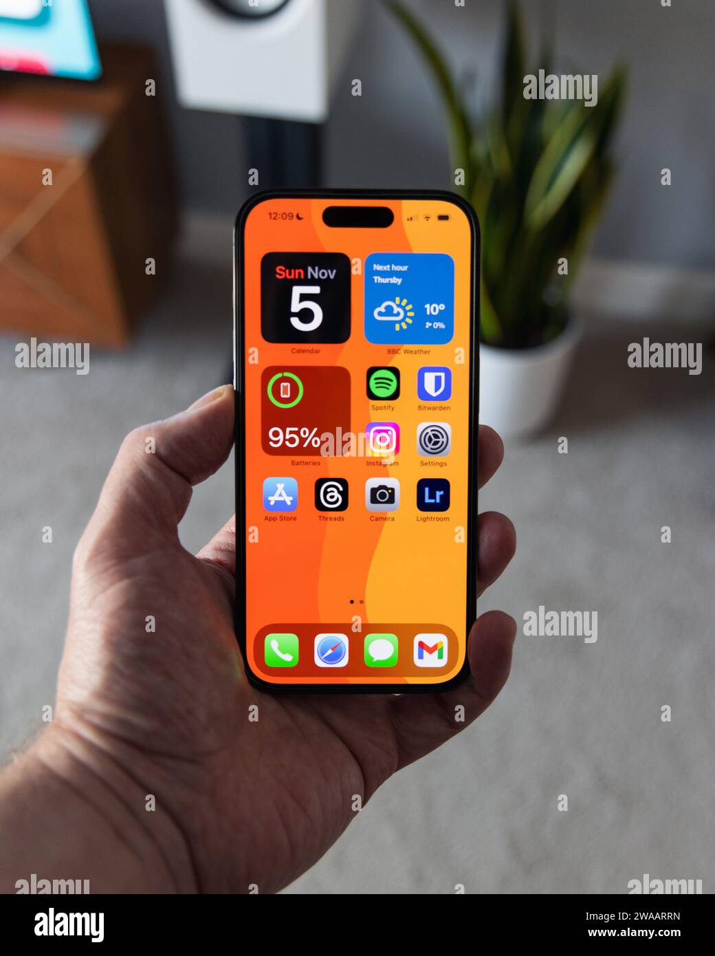 LONDRA - 5 NOVEMBRE 2023: Apple iPhone 14 Pro tenuto in mano con sfondo arancione brillante sullo schermo Foto Stock