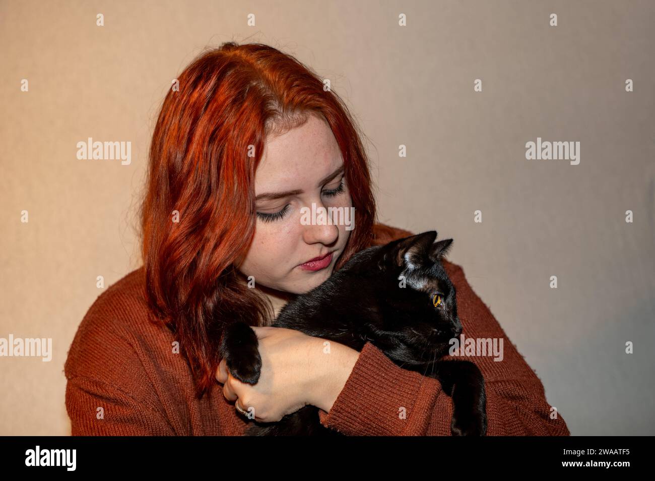 Una ragazza con il suo gatto nero e sfondo bianco Foto Stock