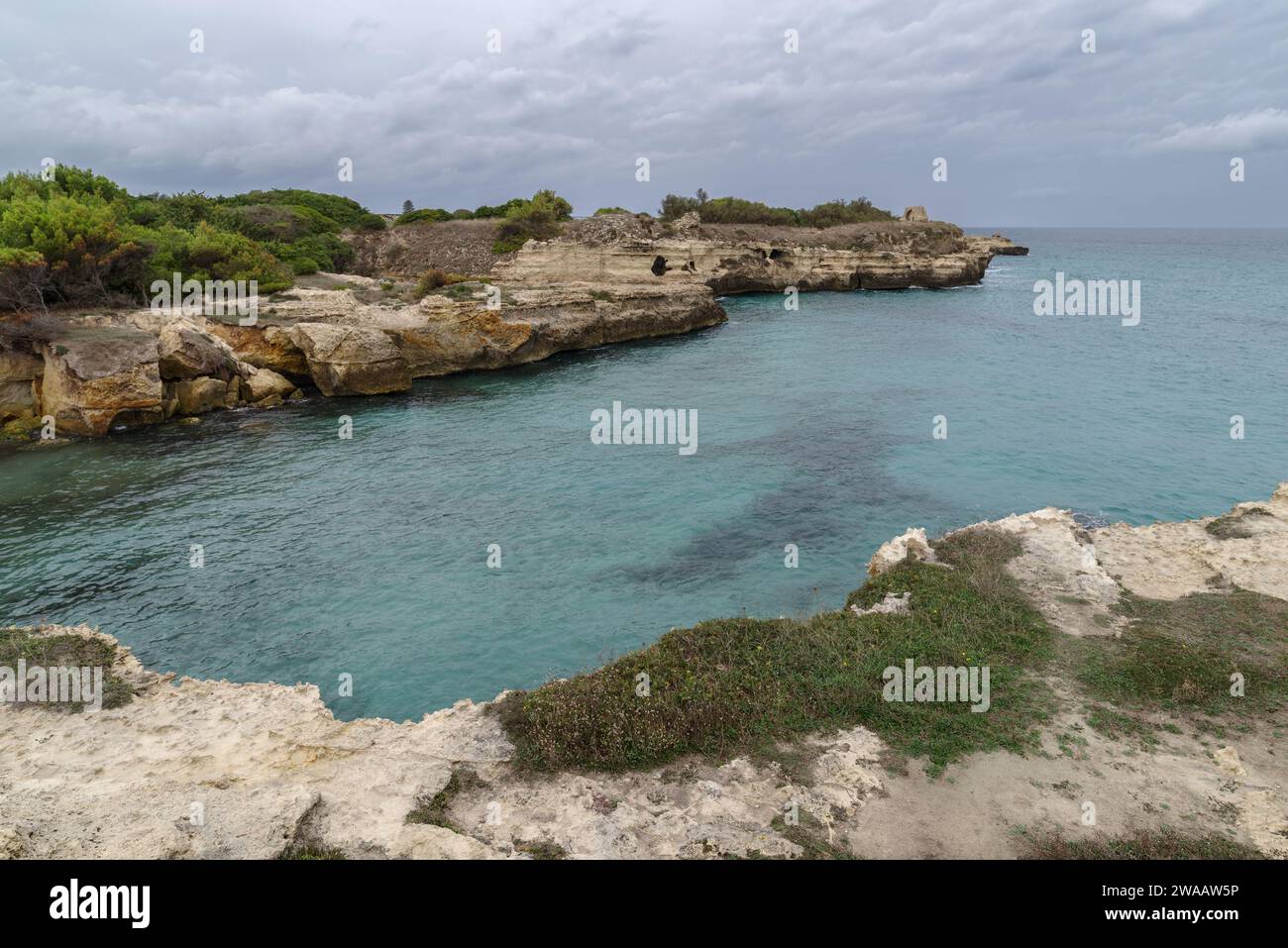 Pozza naturale della Grotta della poesia circondata da aspre scogliere calcaree con grotte e un tunnel che porta al mare aperto. Puglia, Italia Foto Stock