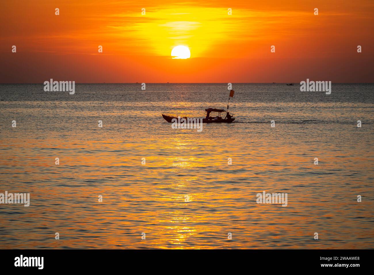 Una piccola barca vietnamita si staglia su un mare calmo al tramonto a Phu Quoc Foto Stock