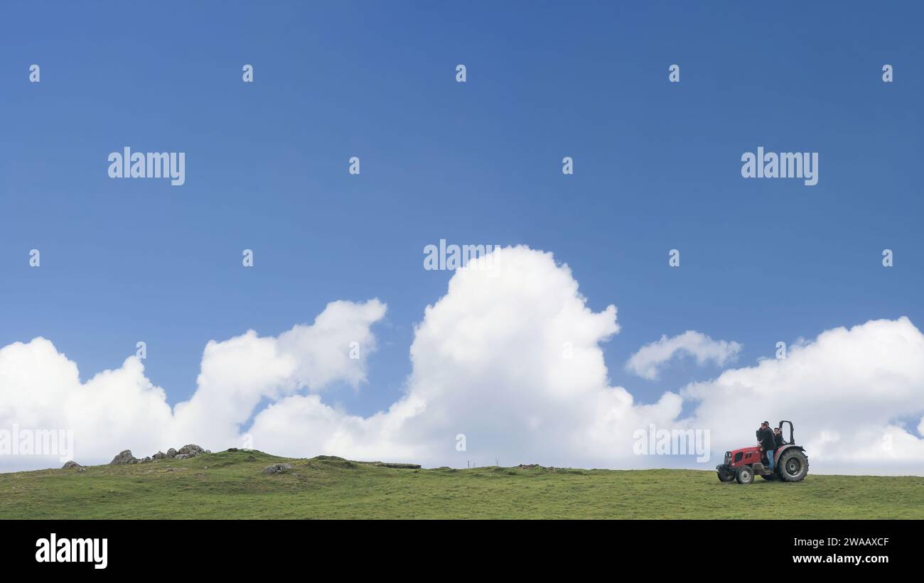 Rize, Turchia - 24 ottobre 2023: Un paio di uomini locali guidano un trattore attraverso il campo, coltivando il terreno fertile, nella regione turca del Mar Nero. Foto Stock