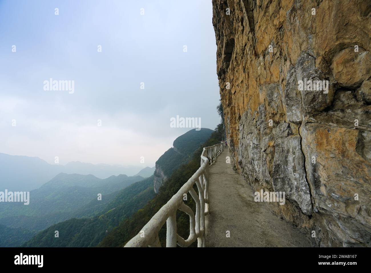 Il sentiero sul muro di montagna è circondato da nuvole e nebbia in lontananza. Topografia carsica della montagna di Jinfo, biodiversità e cultura buddista, C Foto Stock