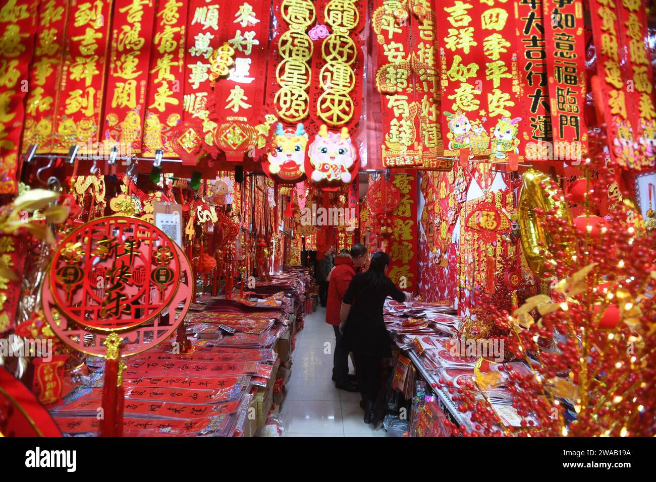 SHENYANG, CINA - 3 GENNAIO 2024 - le persone acquistano distici, lanterne e bambole per la festa di primavera in un mercato all'ingrosso a Shenyang, nel nord-est della Cina Foto Stock