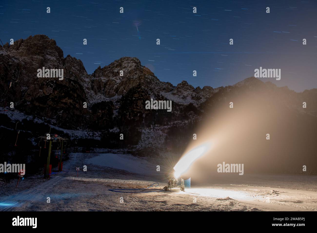 Il cannone spara neve sulla pista da sci mentre è in azione Foto Stock