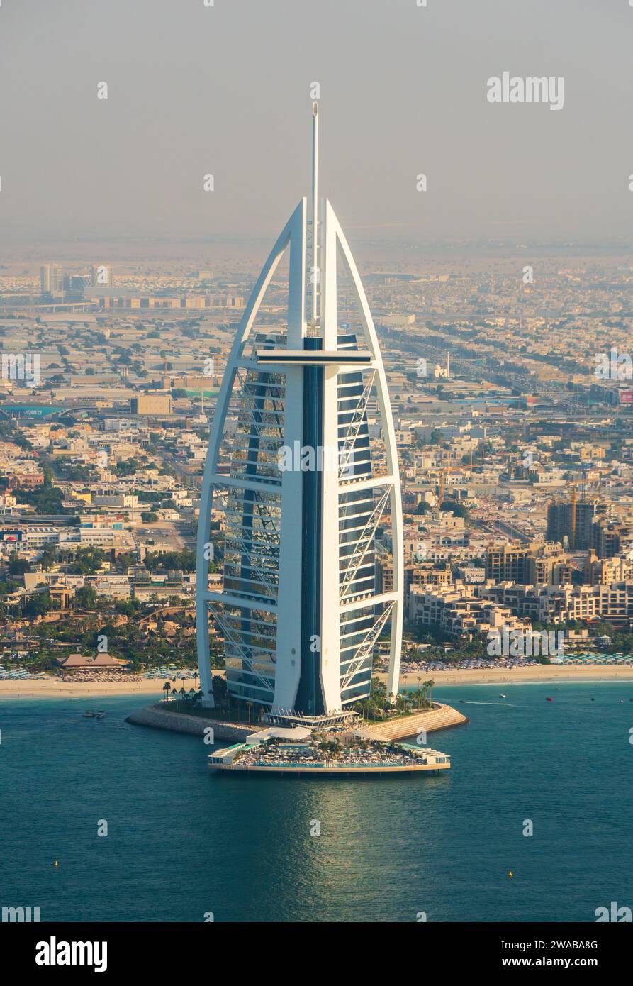 Hotel di lusso Burj al Arab a Dubai, Emirati Arabi Uniti, vista ad alto angolo, area residenziale sullo sfondo, cielo nebbioso, sole pomeridiano. Foto Stock