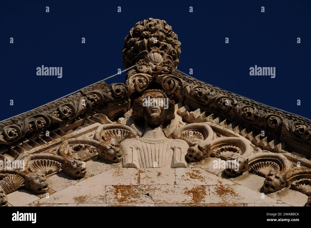 Apice del timpano occidentale della cattedrale di San Marco a Korčula nella contea di Dubrovnik-Neretva, con sontuose decorazioni gotiche degli anni '1400, tra cui conchiglie di capesante e teste di creature immaginarie. Foto Stock