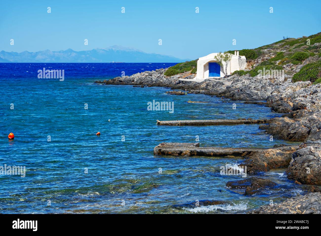 Piccola casa di pescatori bianca sulla riva del mare su un'isola greca Foto Stock