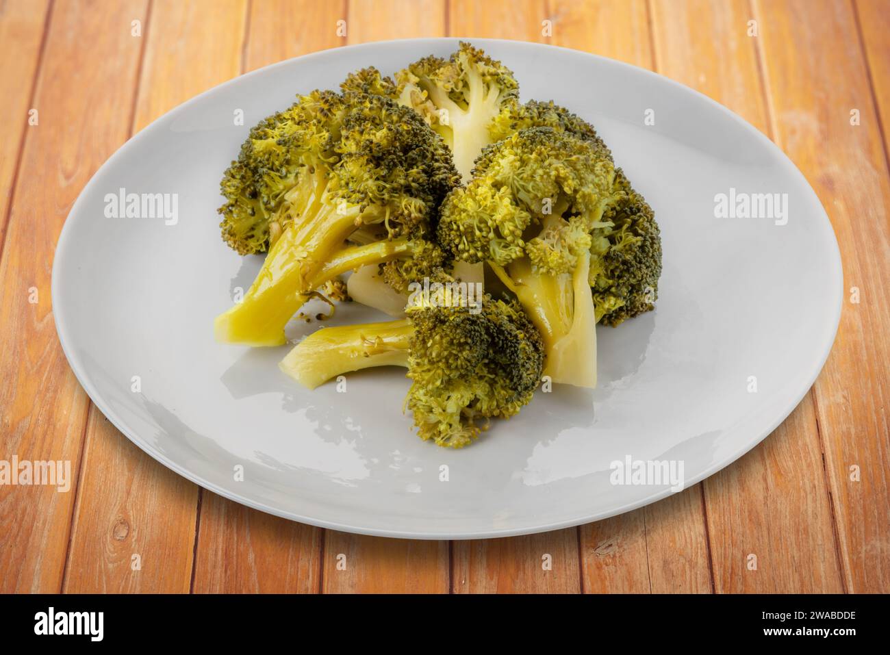 Broccoli bolliti in piatto su tavolo di legno, percorso di ritaglio incluso Foto Stock