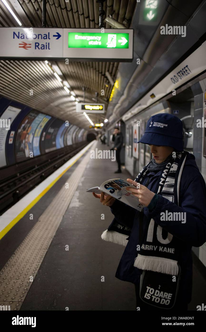 Giovane tifoso di calcio degli Spurs con il suo programma di match day tornando a casa utilizzando la metropolitana di Londra, Inghilterra, Regno Unito Foto Stock