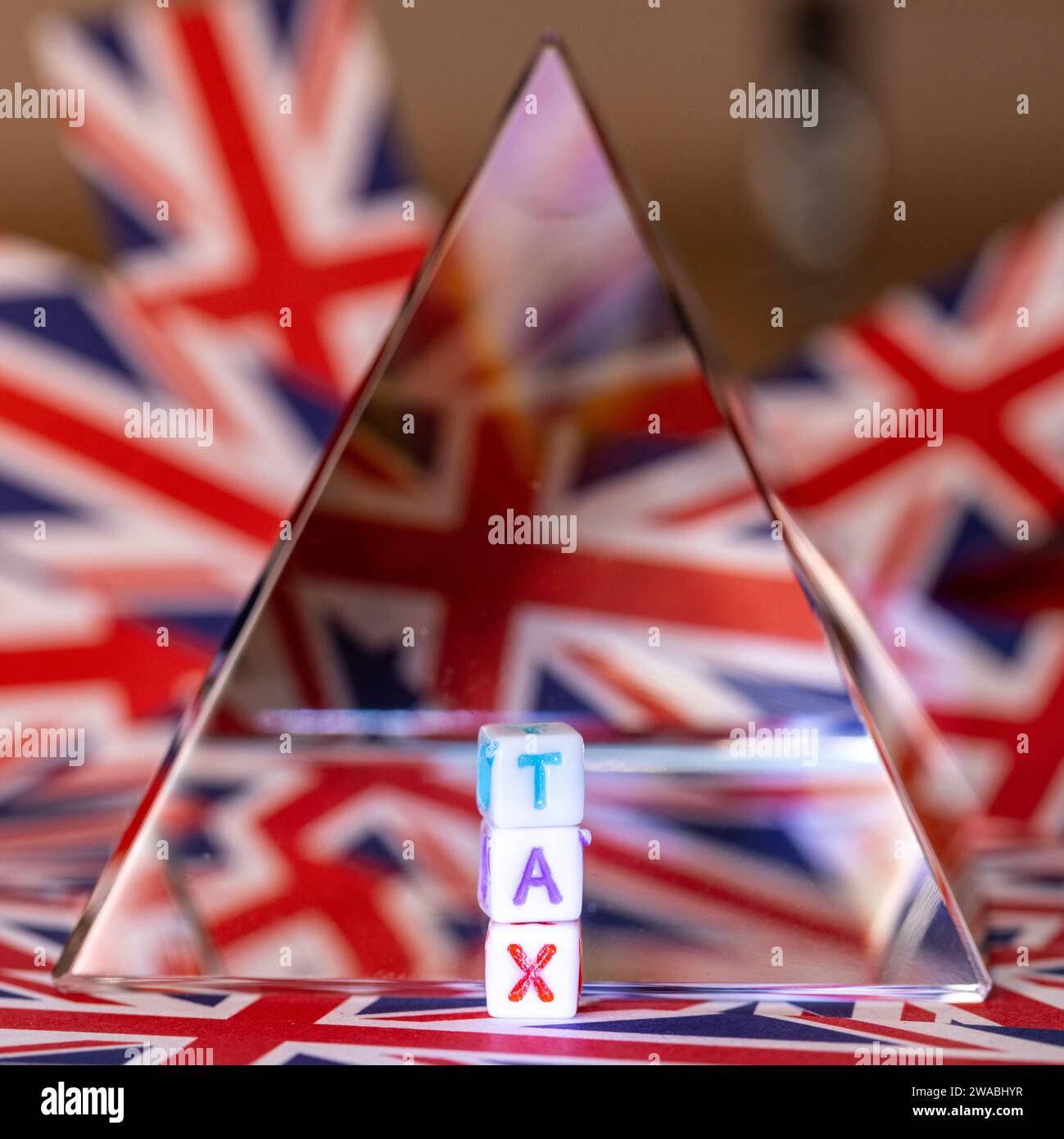 Una piramide di cristallo accanto a lettere di blocco che esprimono LE TASSE, Future of Tax, con lo sfondo della bandiera Union Jack, UK Tax, United Kingdom Taxation Foto Stock