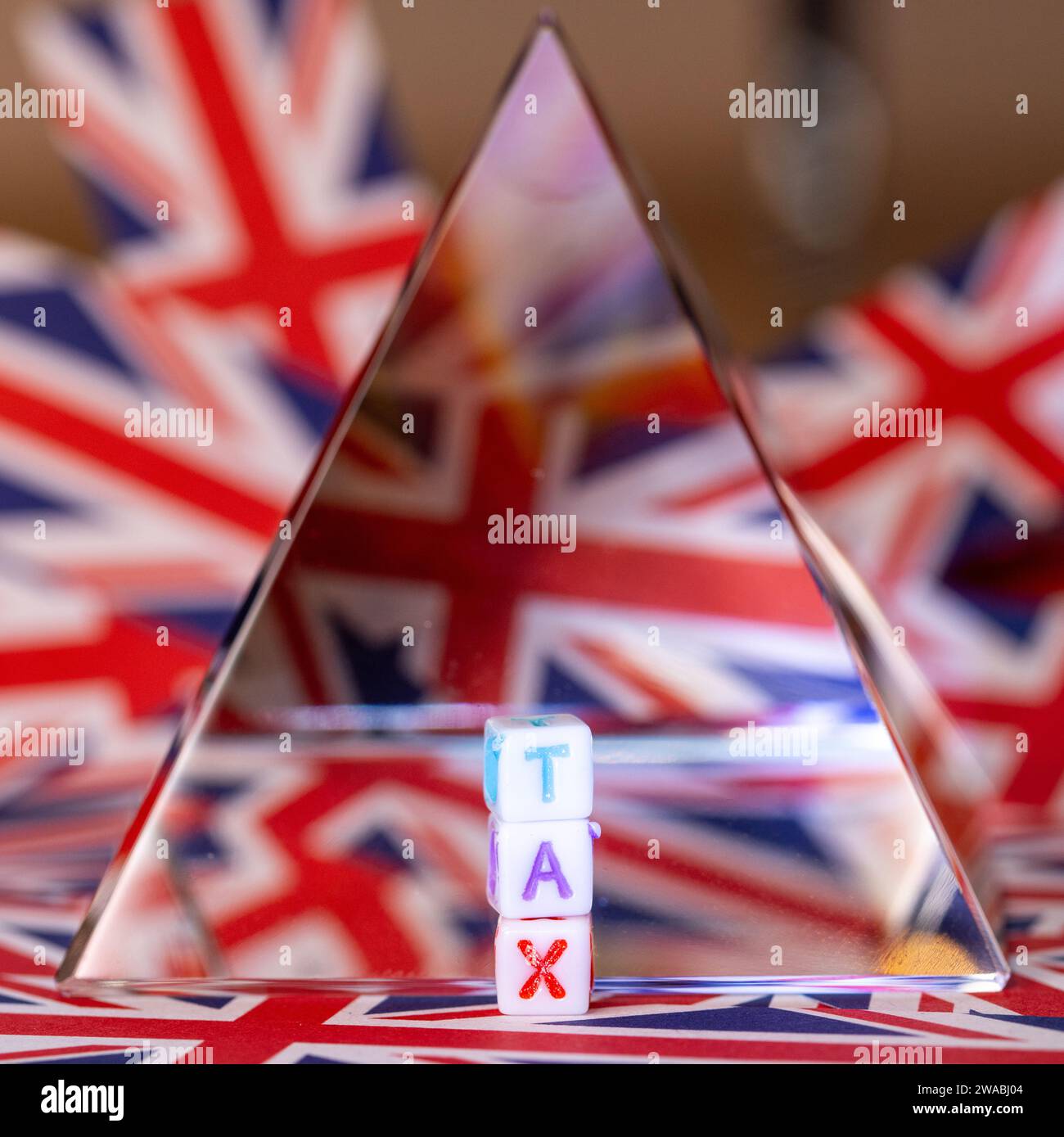 Una piramide di cristallo accanto a lettere di blocco che esprimono LE TASSE, Future of Tax, con lo sfondo della bandiera Union Jack, UK Tax, United Kingdom Taxation Foto Stock
