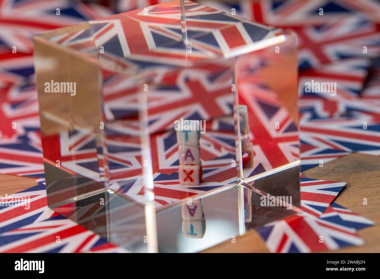 Un cubo di cristallo accanto alle lettere di blocco che indicano LA TASSA, Future of Tax, con lo sfondo della bandiera Union Jack, UK Tax, United Kingdom Taxation Foto Stock