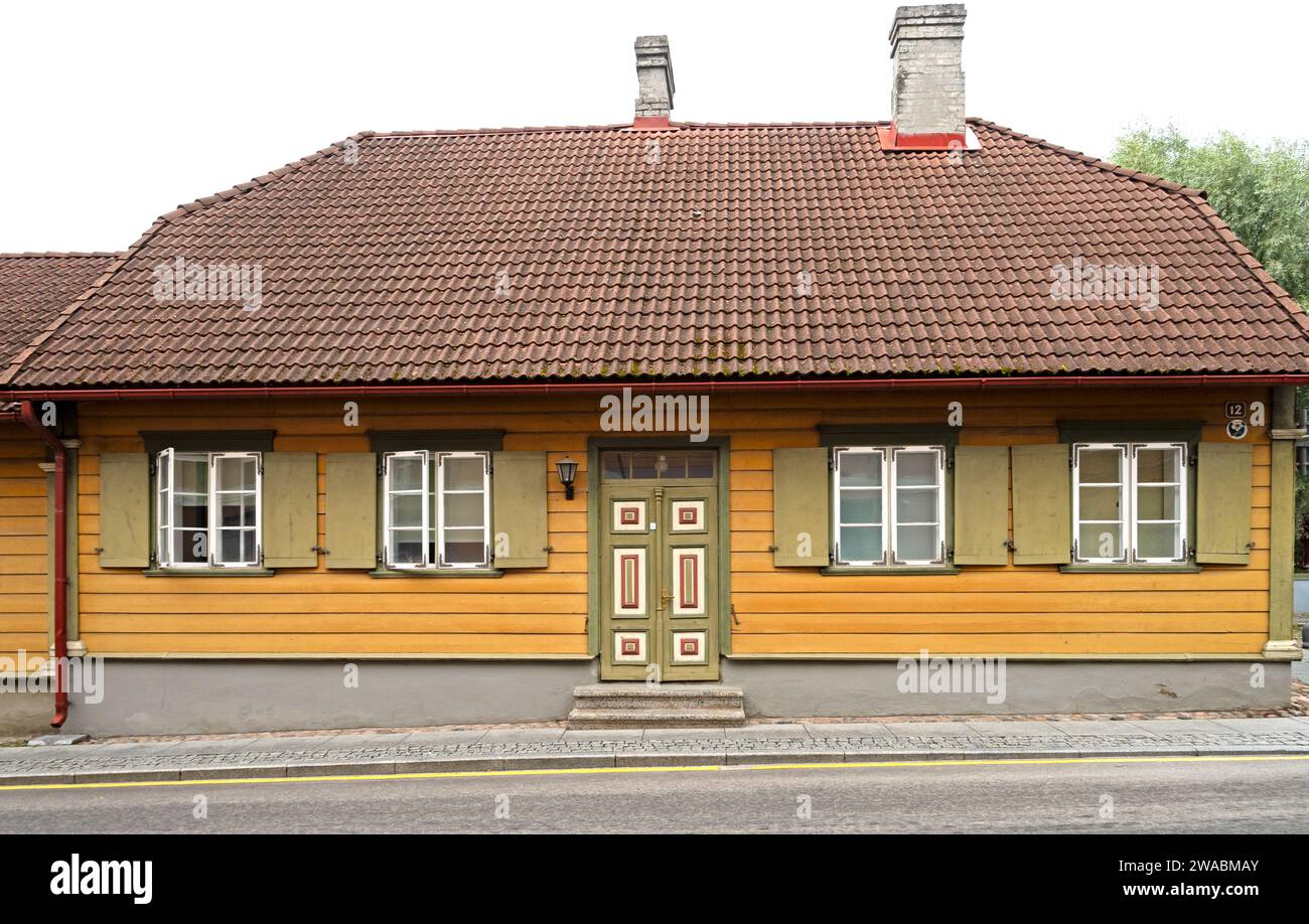 Casa con rivestimento in pannelli di legno giallo, tegole di terracotta, persiane verdi e porta con pannelli di legno dipinti in verde e bianco, Viljandi, Estonia. Foto Stock