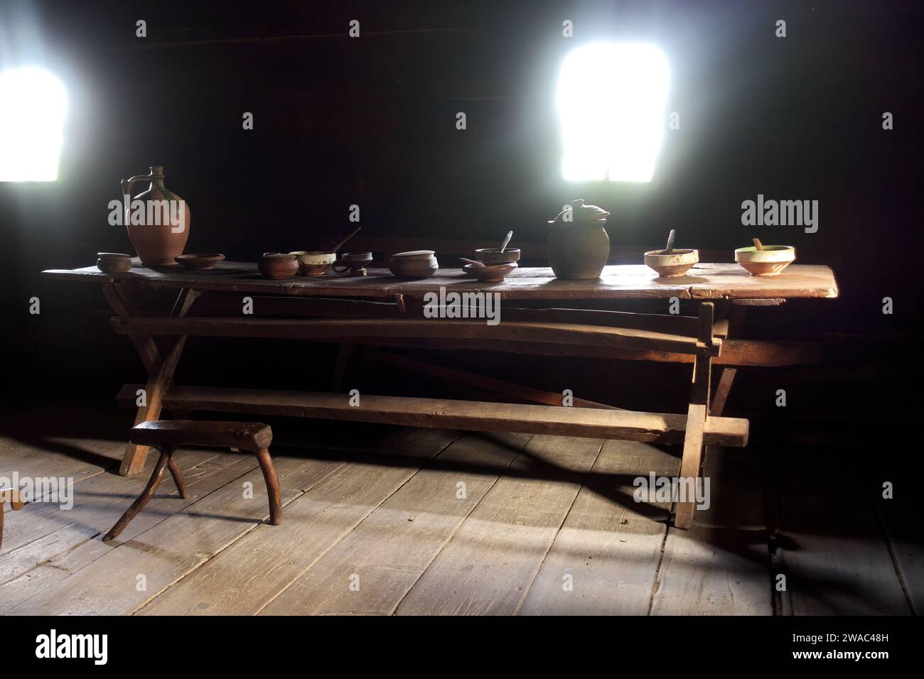 Vecchio tavolo in legno massello con ceramiche, ciotole di argilla e cucchiai di legno all'interno della casa tradizionale serba nel Museo all'aperto Old Village, Sirogojno, Serbia Foto Stock