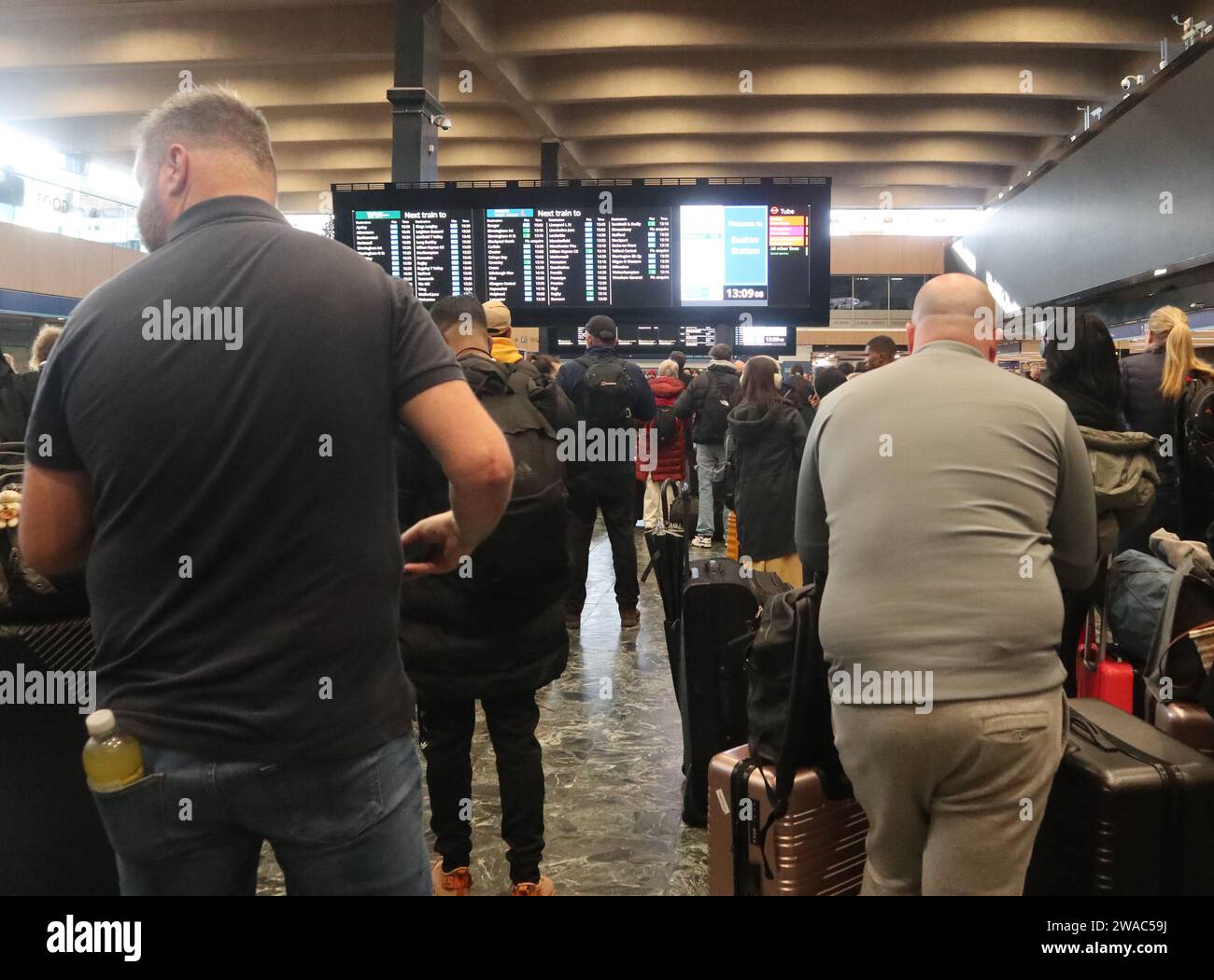 Londra Inghilterra Regno Unito 3 gennaio 2024 i passeggeri attendono informazioni sulla partenza dei treni dalla stazione ferroviaria di Londra Euston tramite le schede di partenza del Customer Information System (CIS). I pannelli di partenza sono prodotti da Infotec. Si tratta di un design a LED RGB a matrice completa. I display sono in grado di visualizzare avvisi grafici avanzati in un formato flessibile e dinamico. I sistemi di visualizzazione sono collegati a sistemi di informazione dei treni in tempo reale per consentire l'aggiornamento automatico. La stazione è gestita da Network Rail ©Ged Noonan/Alamy Foto Stock