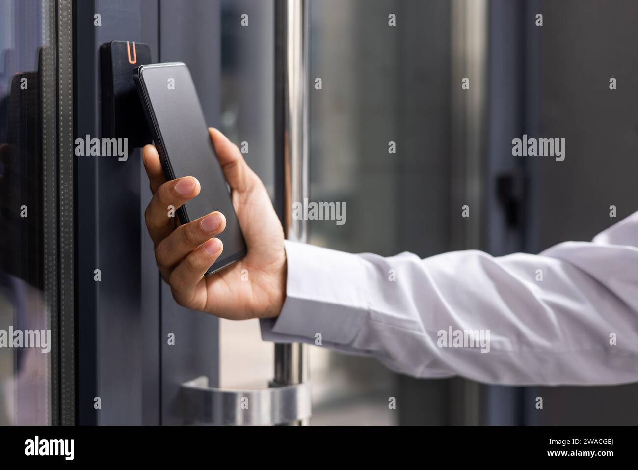 Mano a mano che si avvicina al telefono, l'uomo d'affari utilizza l'applicazione sullo smartphone per rimuovere l'apertura della porta della casa, dell'ufficio. Foto Stock