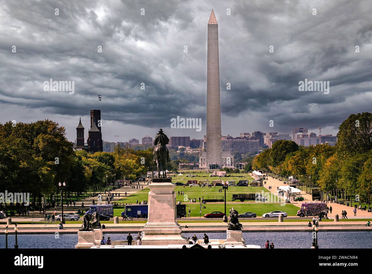 Vista del centro commerciale guardando verso il monumento a Washington sotto i cieli tempestosi con statue e turisti, il vecchio edificio Smithsonian e i camion di cibo Foto Stock