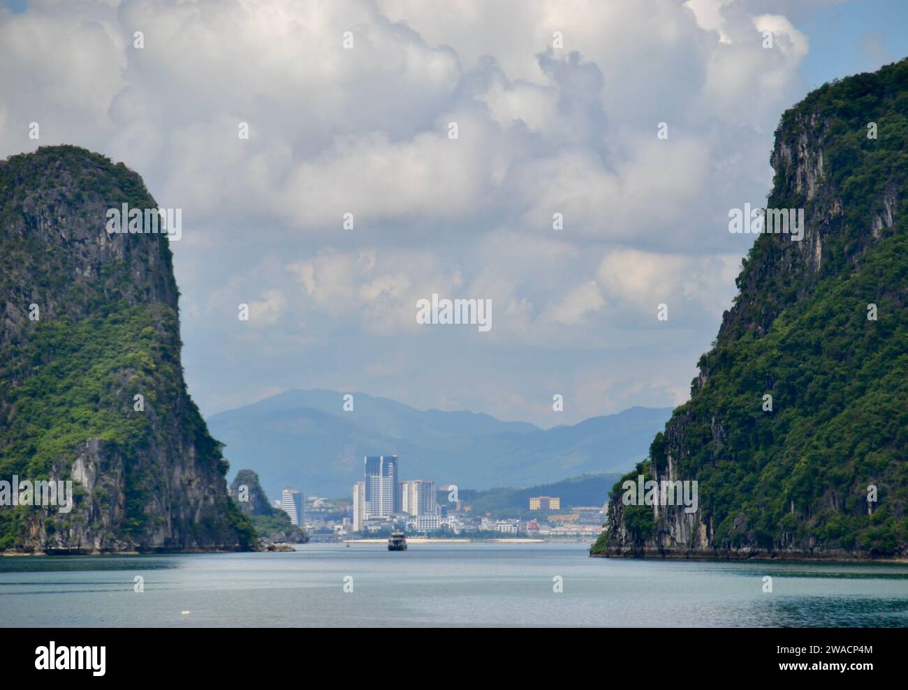 Città di ha Long in Vietnam vista dal porto che guarda indietro attraverso la baia con grandi formazioni carsiche di calcare su ogni lato Foto Stock